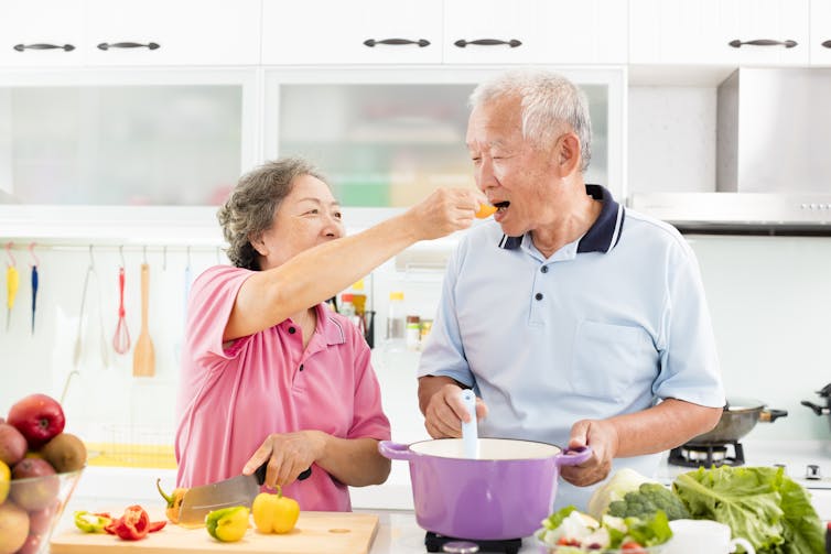 Mulher idosa alimenta um homem idoso com comida em uma colher.